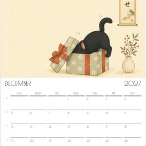 Puede incluir: Una p&aacute;gina de calendario de pared de diciembre de 2027 con una ilustraci&oacute;n de un gato negro dentro de una caja de regalo verde claro con flores blancas y un lazo rojo. A la derecha, un jarr&oacute;n peque&ntilde;o contiene una rama con bayas rojas y un pergamino.