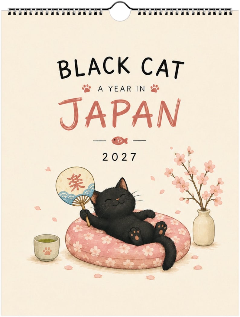 Puede incluir: Un calendario de pared 2027 titulado Black Cat A Year In Japan que muestra a un gato negro sobre un coj&iacute;n rosa con estampado de flores de cerezo, sosteniendo un abanico redondo con texto japon&eacute;s, junto a una taza de t&eacute; y un florero.