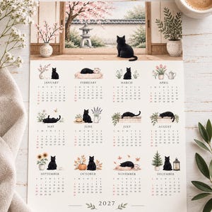 Puede incluir: Un calendario de pared para 2027 con ilustraciones en acuarela de gatos negros en diversos entornos estacionales para cada mes. La sección superior muestra un gato negro sentado en un porche de madera frente a un jardín con una linterna de piedra.