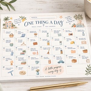 May include: A white paper calendar titled One Thing A Day with a 31-day grid for organization. Each square features a daily decluttering task, small illustrations like a handbag, lemon, or car, and checkboxes. The design includes soft pastel accents.
