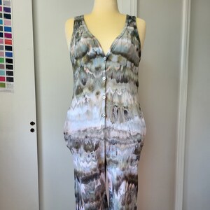 May include: A sleeveless jumpsuit with a button-up front and a tie-dye pattern in shades of green, brown, and white.