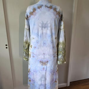 May include: A long-sleeved, light blue, tie-dye dress with brown and green accents. The dress is on a mannequin.
