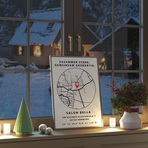 May include: A white poster with a black and white map of a neighborhood with a red pin marking a location. The poster has the text "Zusammen Stark, Gemeinsam Grobartig." and "Salon Bella Am Kleinen Klosterfeld 7 20148 Hamburg 52 12 29.0 N 8 21 2.8 0". The poster is sitting on a windowsill with a small green Christmas tree, two white ornaments, and two white candles.