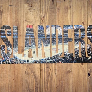 May include: A wood background with the word "ISLANDERS" in large, bold, black letters. The letters are filled with a photo of a hockey arena with fans in the stands and players on the ice.