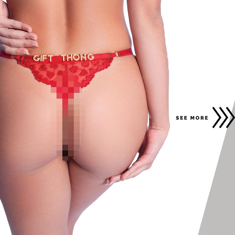 以下が含まれることがあります： 金色の文字で「GIFT THONG」と書かれた赤いTバック。ハート型のレースデザインが特徴です。画像は白い背景に設定されています。