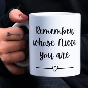 May include: White ceramic mug with black text that reads "Remember whose Niece you are" with a small heart and arrow on the bottom.