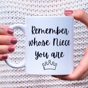 May include: White ceramic mug with black text that reads "Remember whose Niece you are" with a small crown graphic below the text.