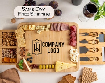 May include: A bamboo cheese board with a built-in drawer for utensils and a separate compartment for snacks. The board is filled with various cheeses, meats, crackers, olives, and nuts. The board also features a personalized logo that says "W COMPANY LOGO".
