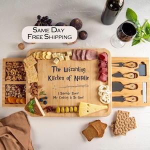 May include: A wooden charcuterie board with the text "The Wizarding Kitchen of Natalie" and a wand graphic. The board is filled with cheese, crackers, meats, nuts, and fruit. A wine bottle and glass are also present.