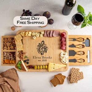 May include: A wooden serving board with a sliding drawer for cheese knives. The board is engraved with a treble clef design and the text "Elena Brooks est. 2020".