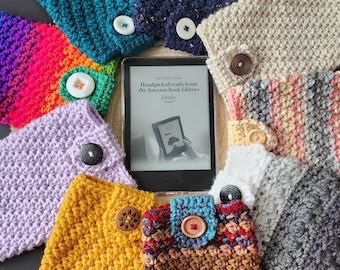 May include: A collection of colorful crocheted Kindle covers with various patterns and buttons. The covers are arranged around a Kindle e-reader displaying the text "Handpicked reads from the Amazon Book Editors".