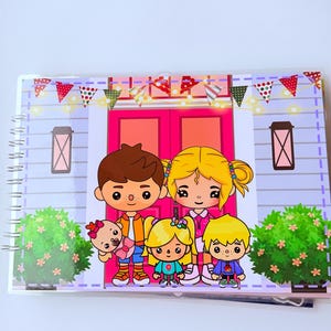 May include: A spiral-bound notebook featuring a cartoon family illustration. The cover depicts a family of five standing in front of a pink door, with a banner that reads "FAMILY" above. The background includes bushes and decorative elements.