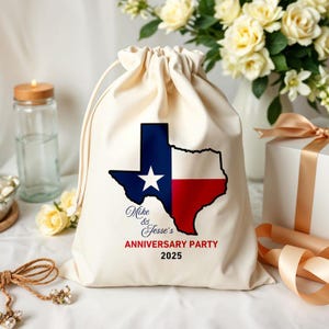 May include: A cream-colored drawstring bag featuring a Texas outline in the state's flag colors: blue, white, and red. The bag is printed with "Mike & Jesse's ANNIVERSARY PARTY 2025" in elegant script and bold red text.