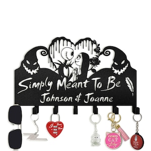 May include: Black metal wall-mounted coat rack with a silhouette of Jack and Sally from The Nightmare Before Christmas. The rack has six hooks and the text "Simply Meant To Be Johnson & Joanne".
