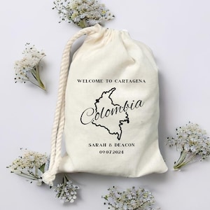 May include: A white cotton drawstring bag with a black outline of Colombia and the text "Welcome to Cartagena, Colombia, Sarah & Deacon 09.07.2024".