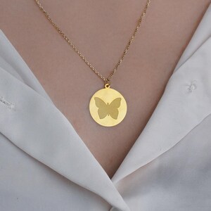 May include: A gold chain necklace with a round pendant featuring a butterfly silhouette.