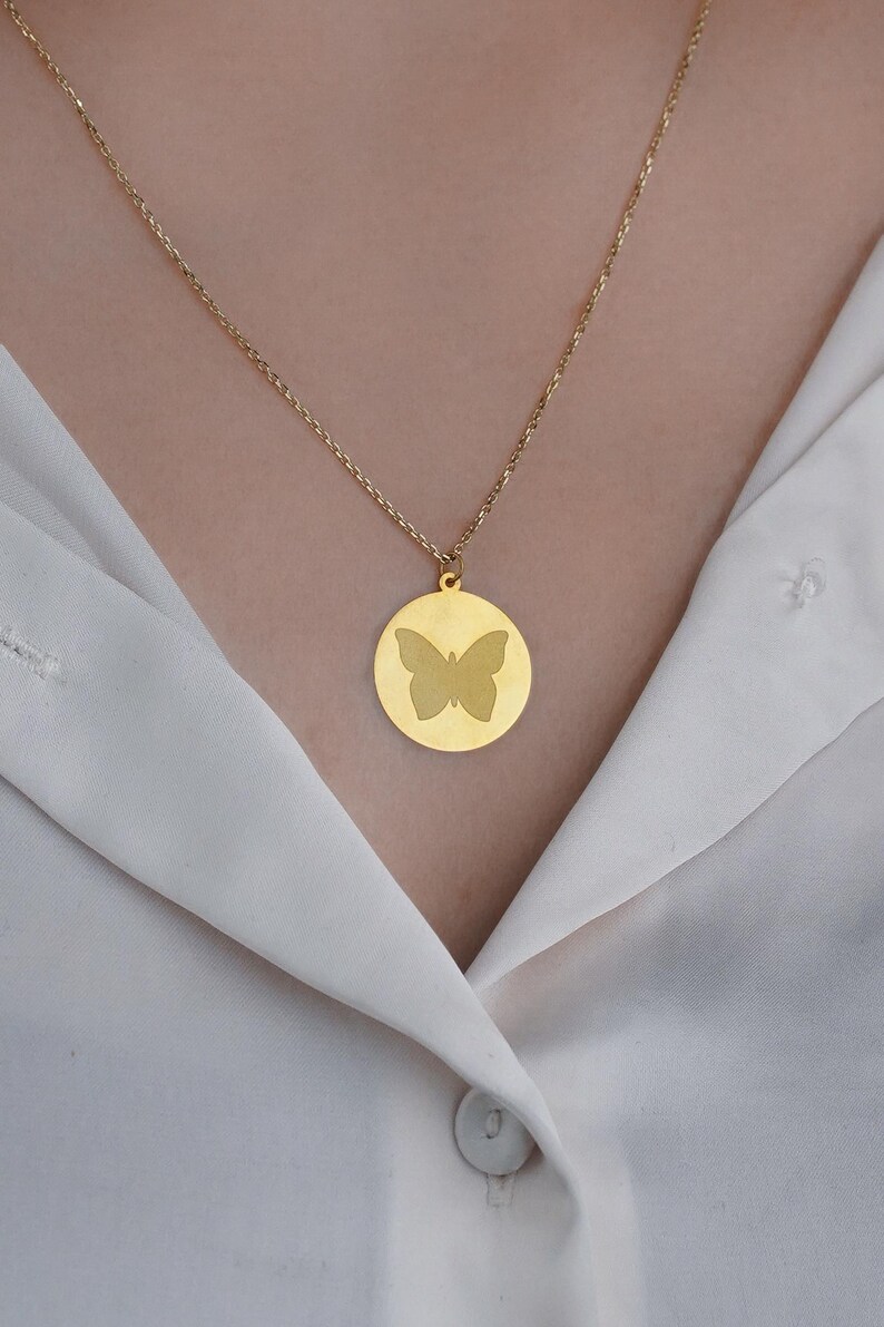 May include: A gold chain necklace with a round pendant featuring a butterfly silhouette.