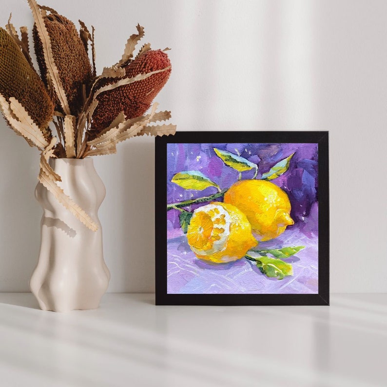 May include: A framed painting of two lemons on a purple background. The lemons are yellow and have green leaves. The painting is in a black frame.