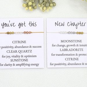 May include: Two cards with the text "you've got this" and "New Chapter" on them. Each card has a bracelet with different colored gemstones and a description of the stones and their meanings.