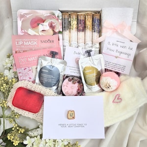May include: A gift box containing five glass vials of bath salts, a peach lip mask, a sakura eye mask, two body cream pouches, a pink bath bomb, a white towel with a pink ribbon, a wish bracelet, a red soap bar, and a card with a toast pin.