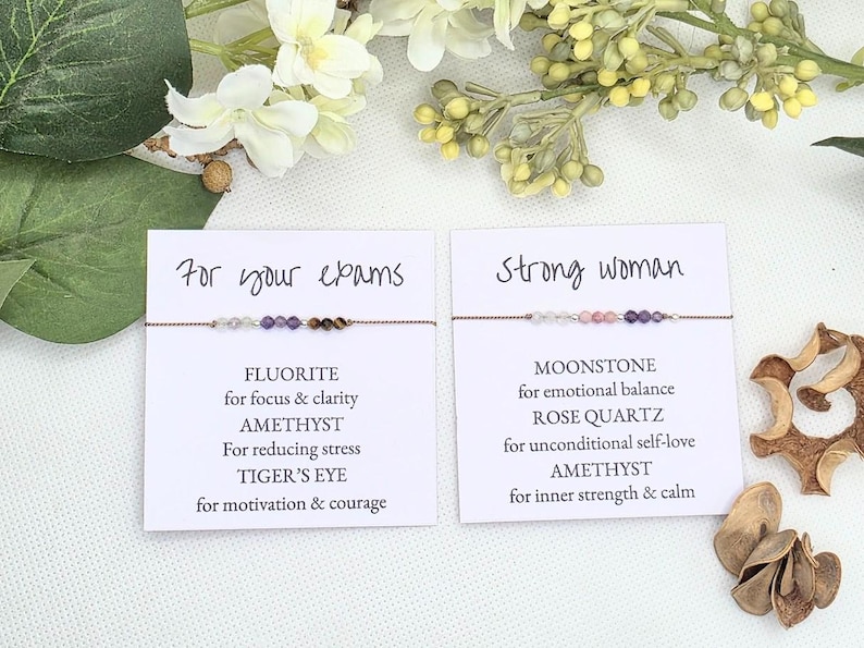 May include: Two cards with text and gemstone bracelets. The first card says "For your exams" and lists the stones: Fluorite, Amethyst, Tiger's Eye. The second card says "Strong woman" and lists the stones: Moonstone, Rose Quartz, Amethyst.