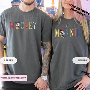 A man and a woman wearing matching t-shirts with the Disney character Mickey Mouse printed on them.