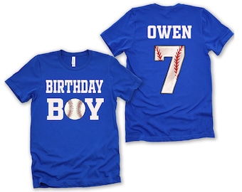 Puede incluir: Una camiseta azul real de manga corta con el texto blanco BIRTHDAY BOY y un gráfico de pelota de béisbol que reemplaza la letra O. La parte posterior muestra el nombre OWEN en blanco sobre un número 7 grande con costuras de béisbol.