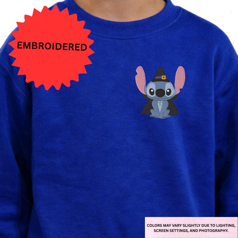 A person wearing a blue sweater with a red starburst and an embroidered character on the front.
