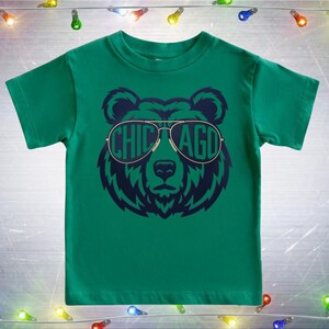A green t-shirt with a graphic of a bear wearing sunglasses and the word "CHICAGO" printed on it.