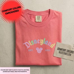 a pink t-shirt with the Disneyland logo and text, along with a tag that says "Comfort Colors" and a label that says "Comfort Colors Watermelon".
