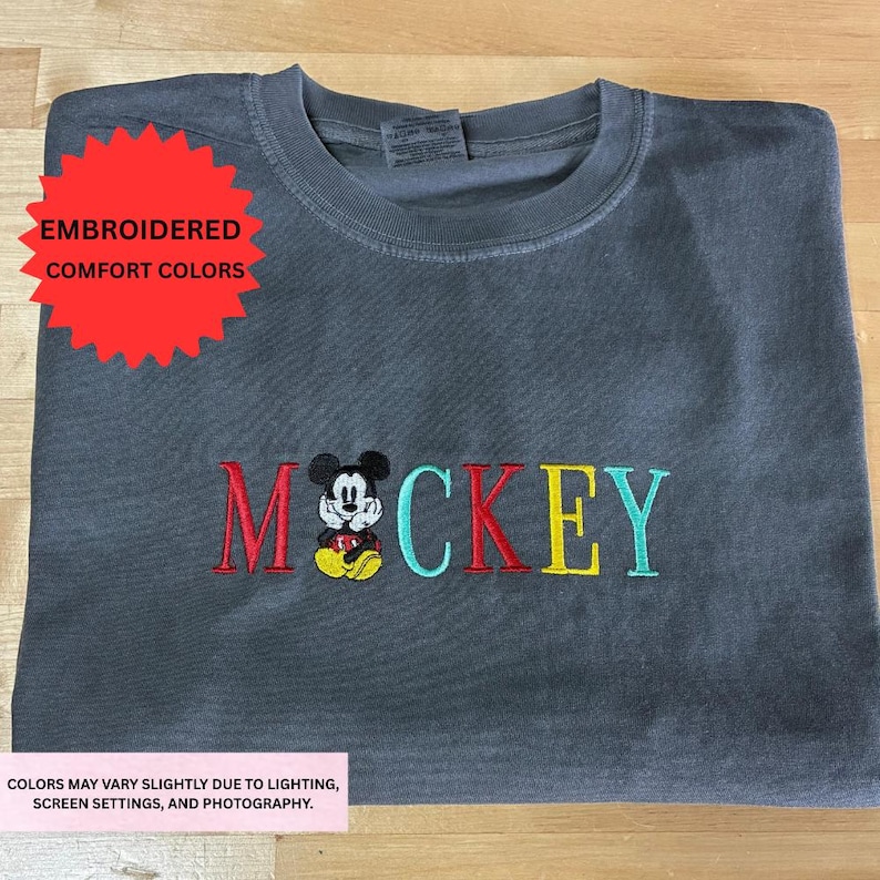 a gray t-shirt with the word "MOCKKEY" embroidered on it, featuring a Mickey Mouse design.