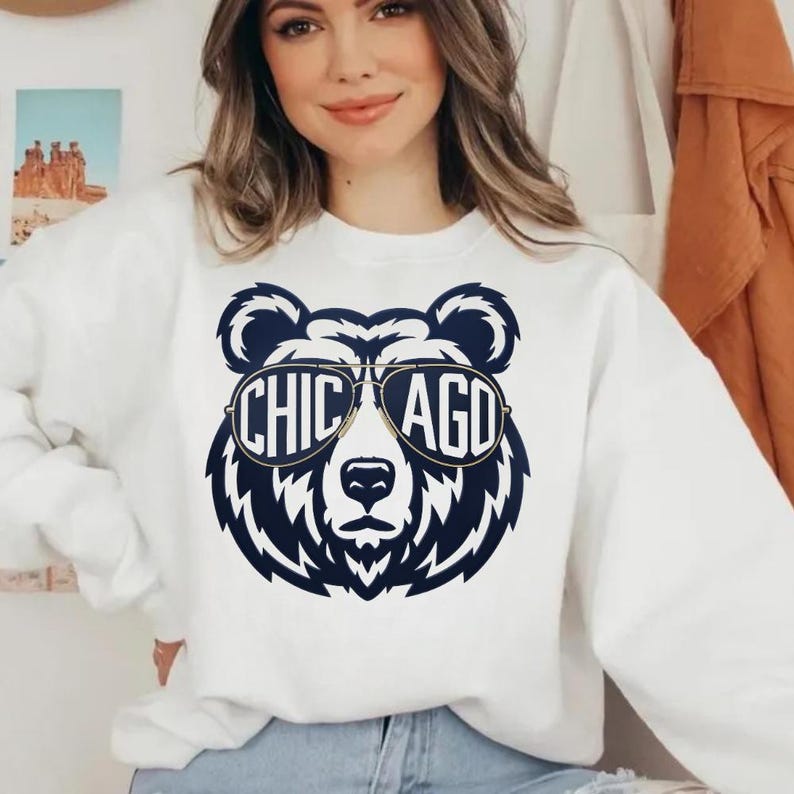 A woman wearing a white sweatshirt with a graphic of a bear wearing sunglasses and the text "CHICAGO" printed on it.