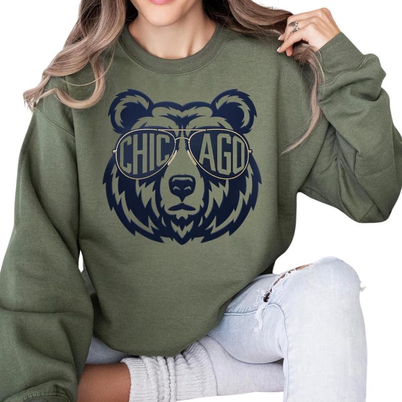 A woman wearing a green sweatshirt with a graphic of a bear wearing sunglasses and the text "CHICAGO" printed on it.