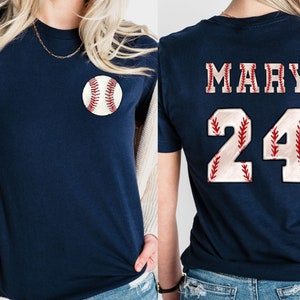 May include: A navy blue t-shirt with a baseball graphic on the front and the name "MARY" and the number "24" on the back. The numbers and letters are white with red stitching.