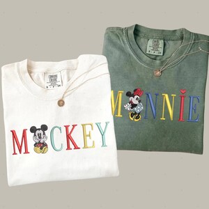 two t-shirts with the word "MICKEY" printed on them, along with images of Mickey Mouse.