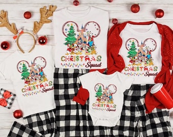 May include: White t-shirts and a baby onesie with a Mickey Mouse design, Christmas tree, and the text "Christmas Squad". Black and white plaid pajama pants and a red cardigan are also in the image. Decorative reindeer antlers and red ornaments complete the holiday theme.