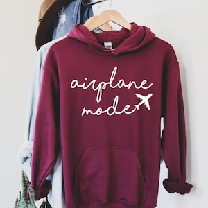 May include: Burgundy hoodie with a white graphic that says "airplane mode" with a small airplane icon.