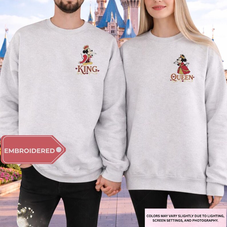 A man and a woman standing together, both wearing matching white sweatshirts with the text "KING" and "QUEEN" printed on them.