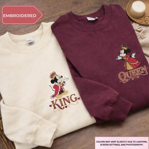 two sweatshirts with a Disney character design, one white and one burgundy, both with the text "King" printed on them.