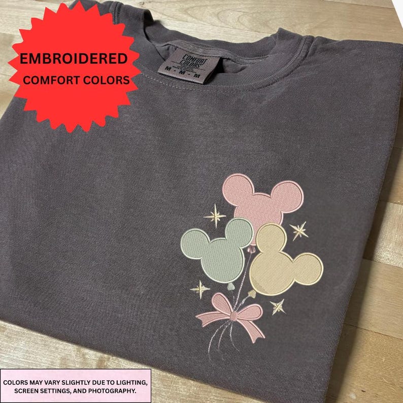 a gray t-shirt with a colorful Mickey Mouse-themed embroidered design on the front.
