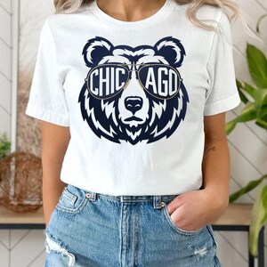 A white t-shirt with a graphic design of a bear wearing sunglasses and the text "CHICAGO" printed on it.