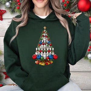 A person wearing a green hoodie with a Christmas tree design made of bowling pins and ornaments.