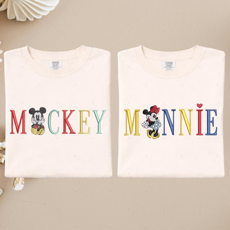 two white t-shirts with the word "MACKKEY" and the name "MANNIE" printed on them, along with illustrations of Mickey Mouse and Minnie Mouse.