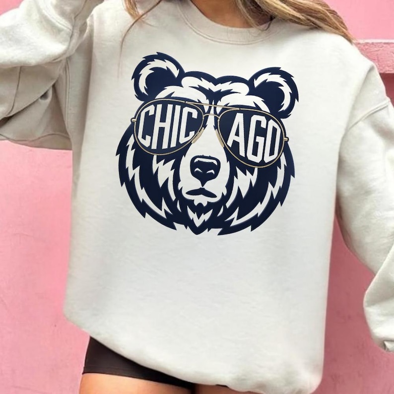 A white sweatshirt with a graphic design of a bear wearing sunglasses and the text "CHICAGO" printed on it.