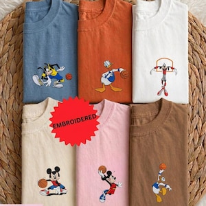 A collection of t-shirts featuring cartoon characters, including Mickey Mouse, Donald Duck, Goofy, and other basketball players, along with basketballs.