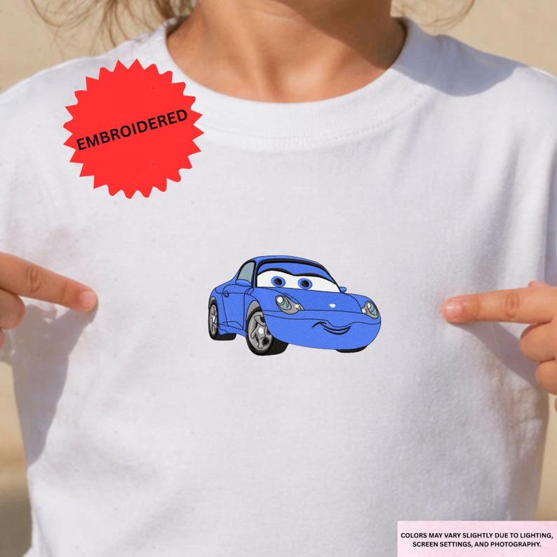 A person is wearing a white t-shirt with a blue cartoon car printed on it.