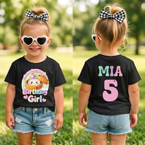May include: A black short-sleeved t-shirt featuring a graphic of a smiling dumpling in a bamboo steamer with a rainbow and the text Birthday Girl on the front, and the name MIA and the number 5 in pastel colors on the back.