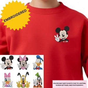 The image is a red sweater with a large yellow starburst on the left side and a collage of six different cartoon character illustrations on the right side.