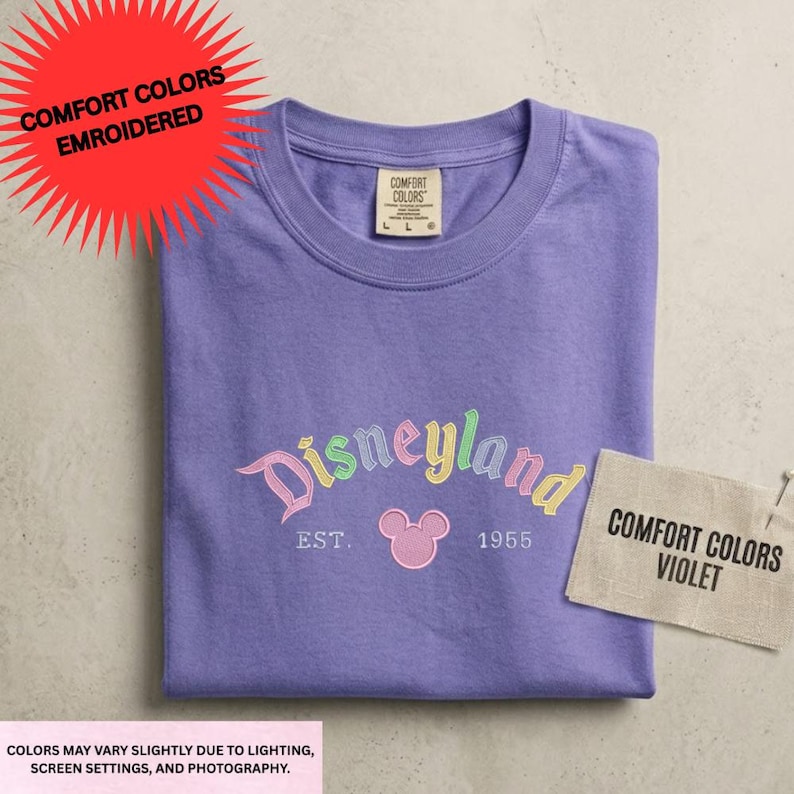 a purple t-shirt with the Disneyland logo and text, along with a tag that says "Comfort Colors Violet" and a red starburst that says "COMFORT COLORS EMBROIDED".