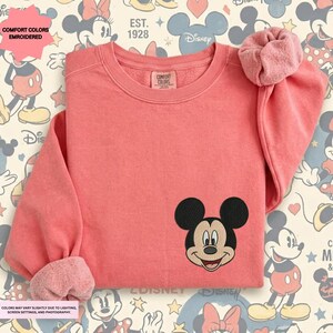 a pink long-sleeved shirt with a Mickey Mouse embroidered logo on the front.